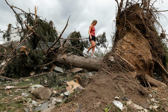 An unidentified child walks on the trunk of a fallen tree Wednesday, May 29, 2019, in Dayton, Ohio, as cleaning efforts begin in a neighborhood damaged by a tornado storm system that passed through the area on Monday.