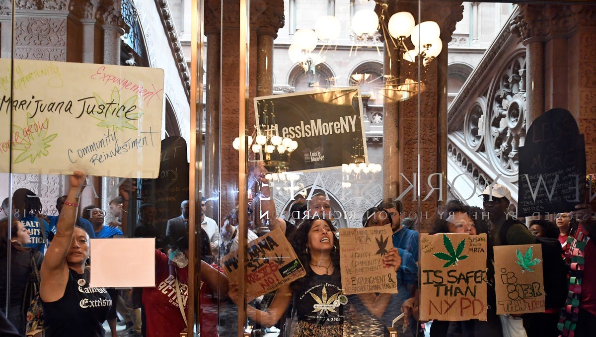 Protesters urging legislators to pass Marijuana legislation holds a signs against the senate lobby doors at the state Capitol Wednesday, June 19, 2019, in Albany, N.Y. (AP Photo/Hans Pennink)