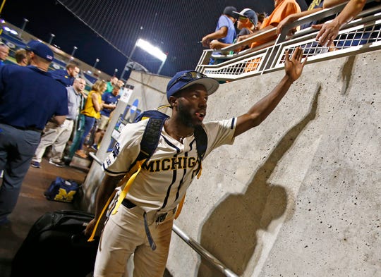 Michigan left fielder Christan Bullock greets fans as he leaves the field after Michigan defeated Vanderbilt in Game 1 of the College World Series.