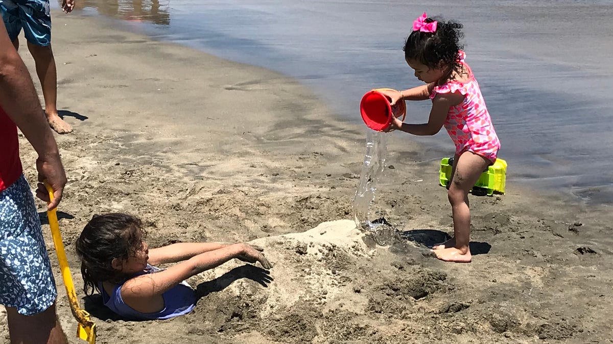 Alis Zuniga pours a bucket of seawater on her half-buried friend at Cabrillo Beach in the San Pedro section of Los Angeles. Though it is clean most days,  the beach can have high bacteria counts at certain times of year.