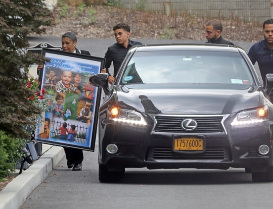 A woman carries a poster with photos of 1-year-old twins, Luna and Phoenix Rodriguez for their wake at Sinatra Memorial Home in Yonkers Aug. 2, 2019.
