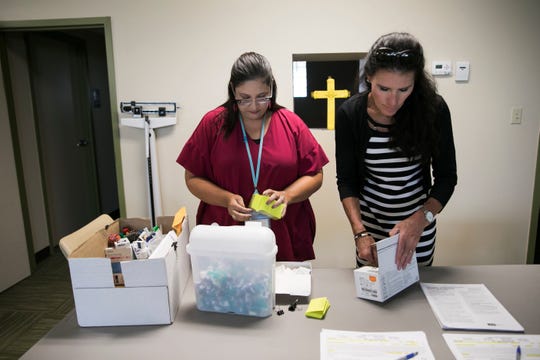 Summit County Public Health nurse Rachel Flossie, left, and communicable disease supervisor Tracy Rodriguez prepare to give vaccinations to clients during a South Street Ministries program in Akron, Ohio, on July 23, 2019.