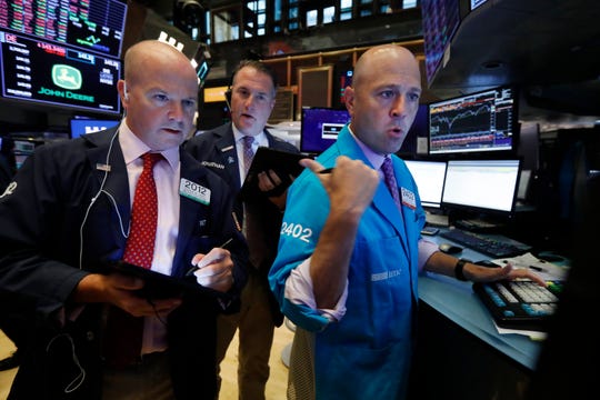 Traders Patrick Casey, left, and Jonathan Corpina, center, work with specialist Jay Woods on the floor of the New York Stock Exchange, Wednesday, Aug. 14, 2019.