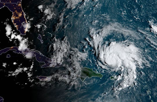 This satellite image obtained from NOAA/RAMMB, shows Hurricane Dorian (R) as it passes Puerto Rico at 11:30 central time on August 29, 2019. The National Hurricane Center (NHC) in Miami said the hurricane watch and tropical storm warning for the island had been lifted, and that 