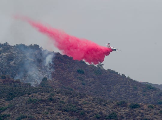 A Cal Fire aircraft drops fire retardant on the Tenaja fire in the Murrieta foothills near Vineyard Parkway, September 5, 2019.