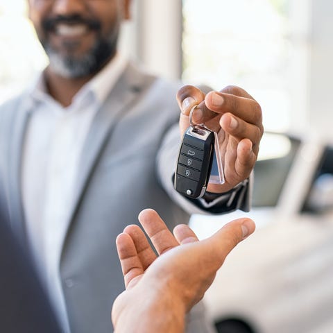 Closeup hand of cardealer giving new car key to cu