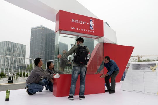 Workers dismantle signage for an NBA fan event scheduled to be held on Wednesday night at the Shanghai Oriental Sports Center in Shanghai, China on Tuesday. Chinese state broadcaster CCTV announced Tuesday it will no longer air two NBA preseason games set to be played in the country.