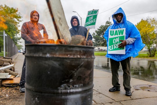 UAW autoworkers Davor Janceski, 41, of Macomb; Edward LeBlanc 48, of Lincoln Park and Martin Jackson, 68, of Detroit keep warm near a burn barrel while they strike in the rain in front of the General Motors Detroit-Hamtramck assembly plant in Hamtramck, Mich. on Wednesday, Oct. 16, 2019. General Motors and the UAW reached a proposed tentative agreement on a new contract Wednesday, the 31st day of a nationwide strike. 