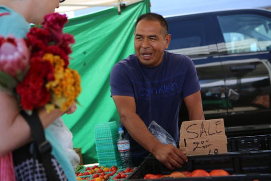 Mario Julian of Nest Farms talks to a customer at the Joshua Tree Certified Farmers' Market in Joshua Tree, Calif., on Saturday, October 19, 2019. 