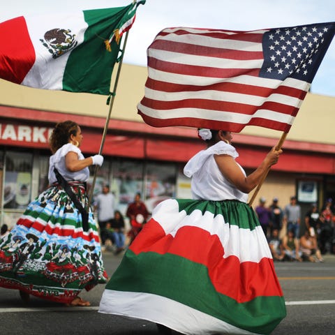 Performers carry the Mexican and U.S. flags in a p