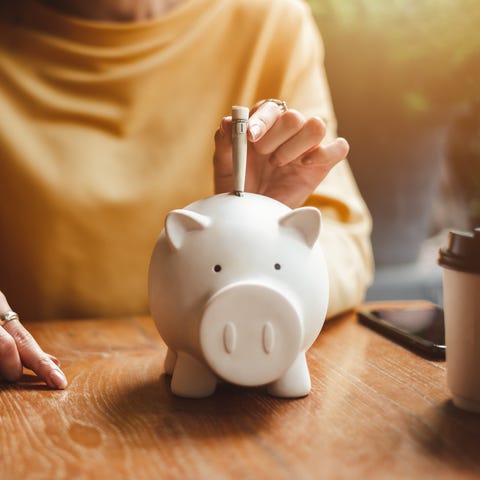 woman hand putting money bank note dollar into pig