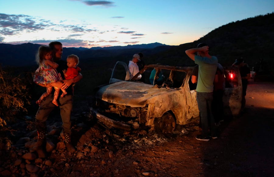 Members of the LeBaron family look at a burned car that carried some of the nine family members who were ambushed and killed in Bavispe, Sonora mountains, Mexico.