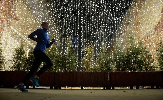 A jogger runs by a curtain of lights as Christmas decorations, provided by Evansvilleâ€™s Economic Improvement District, gives a festive touch to Main Street Thursday evening. The EID, provides help with trash removal, ice and snow removal and special events wraps up its first calendar year in business, December 19, 2019.