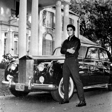 Elvis Presley poses in front of his home with his Rolls Royce in October 1960. Back home after a stint of movie-making in Hollywood, Elvis proudly posed with the latest mark of his fame: a brand-new black Standard Salon Silver Cloud II Rolls Royce worth around $18,000.
