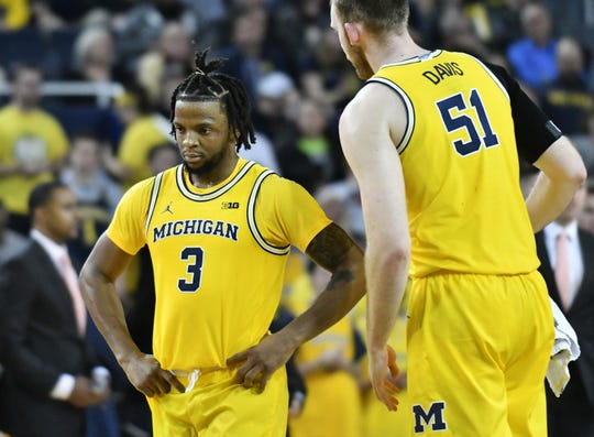 Michigan guard Zavier Simpson (3) heads to the bench for a timeout with Michigan forward Austin Davis (51) in the second half Wednesday night in Ann Arbor.