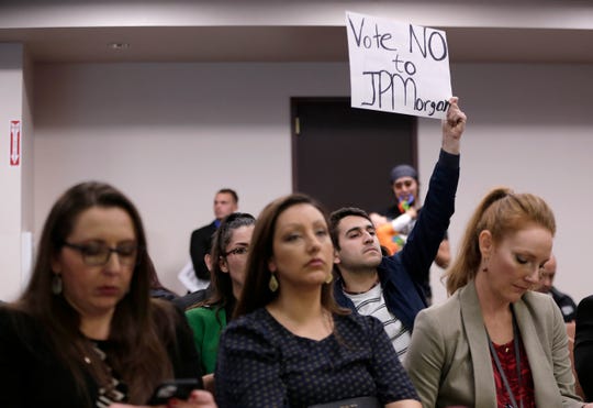 Miguel Escoto, a Sunrise El Paso enviromental group coordinator, holds a sign urging City Council to not allow the transfer of El Paso Electric's city franchise to a JPMorgan-tied investment fund at Council's Feb. 4 meeting.