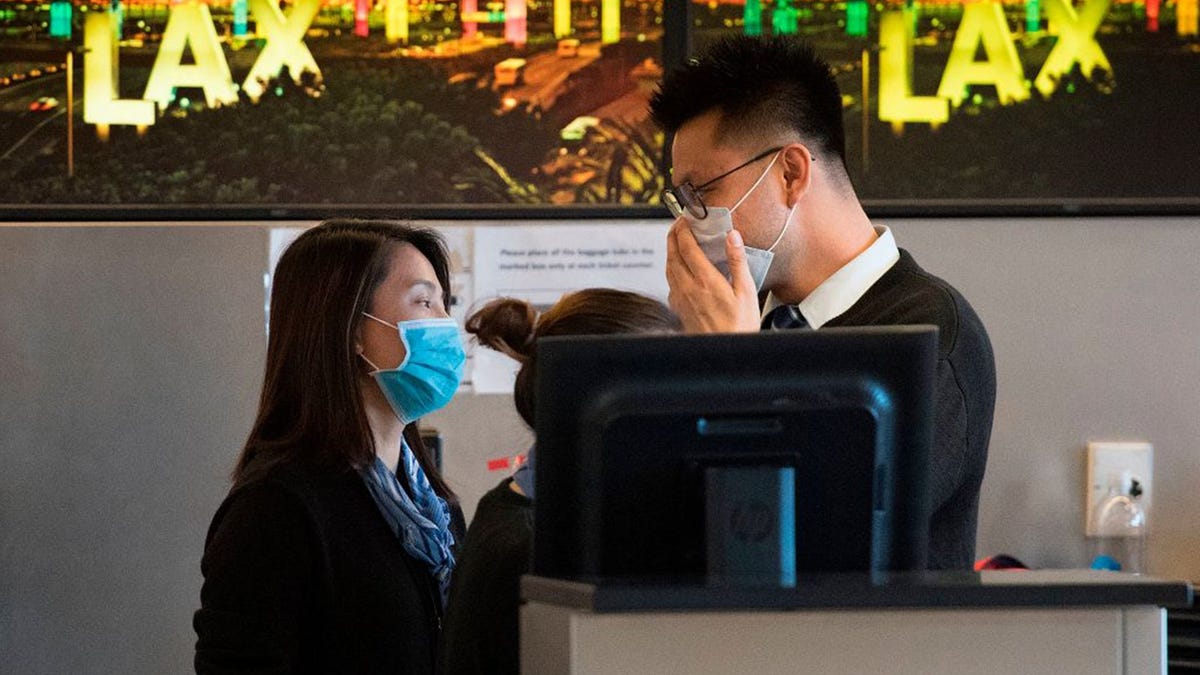 Airline check in staff wear face masks to protect against the spread of the Coronavirus at the Los Angeles International Airport, California, on January 29, 2020.