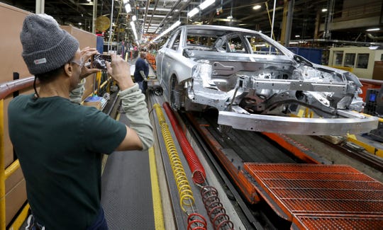 Gregory Edwards, 64, of Detroit takes pictures of the last 2020 Chevrolet Impala as it made its way down the production line on Thursday inside the GM Detroit-Hamtramck Assembly plant.