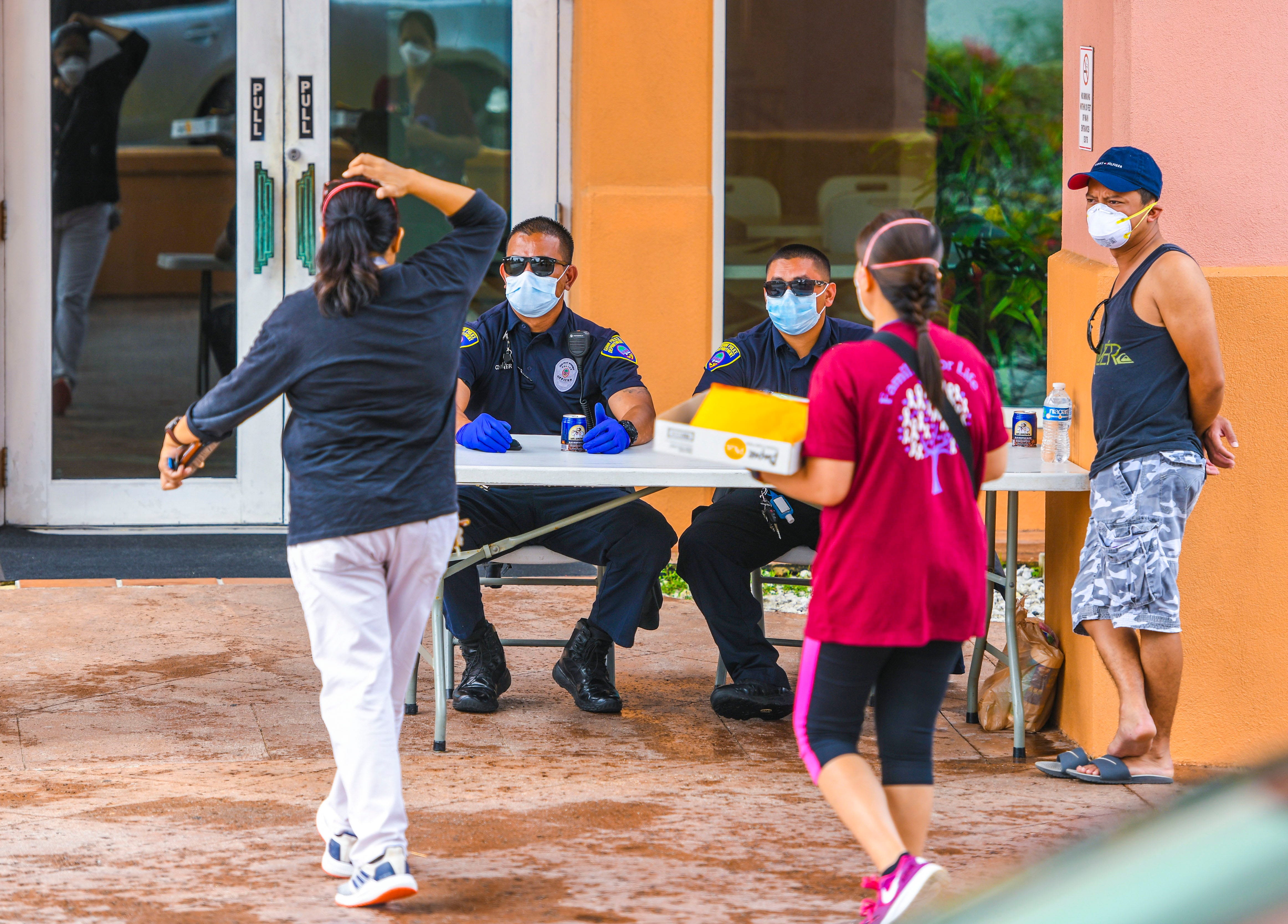 Visitors are greeted by Guam Police Department officers at the entrance to the Hotel Santa Fe in Tamuning in this March 21, 2020, file photo.