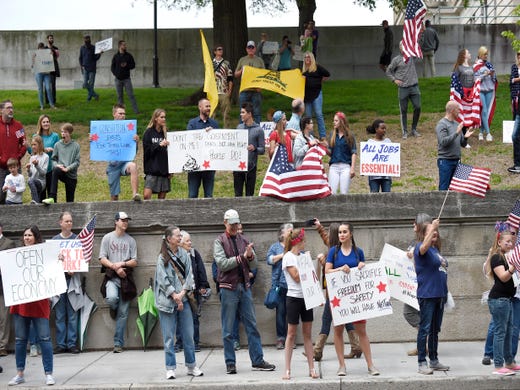 Protesters hold signs and flags during the rally against the stay-at-home orders at the State Capitol Sunday, April 19, 2020 in Nashville, Tenn. 