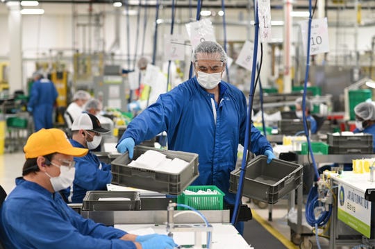 Nick Sinishyaj, center, gathers finished face masks made at the Warren transmission plant on Thursday, April 23, 2020.