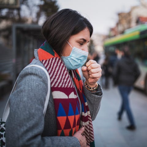 Side view of woman wear face mask and coughing whi