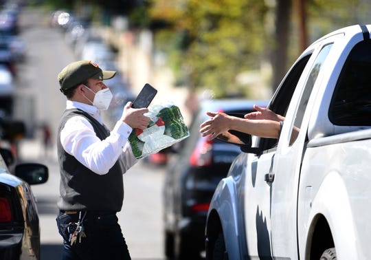 Mildred Casado Mayor's assistant, hands a pack of water bottles to a driver as the City of Passaic is giving out cases of bottled water to its residents at Dignity House in Passaic on 05/03/20. 