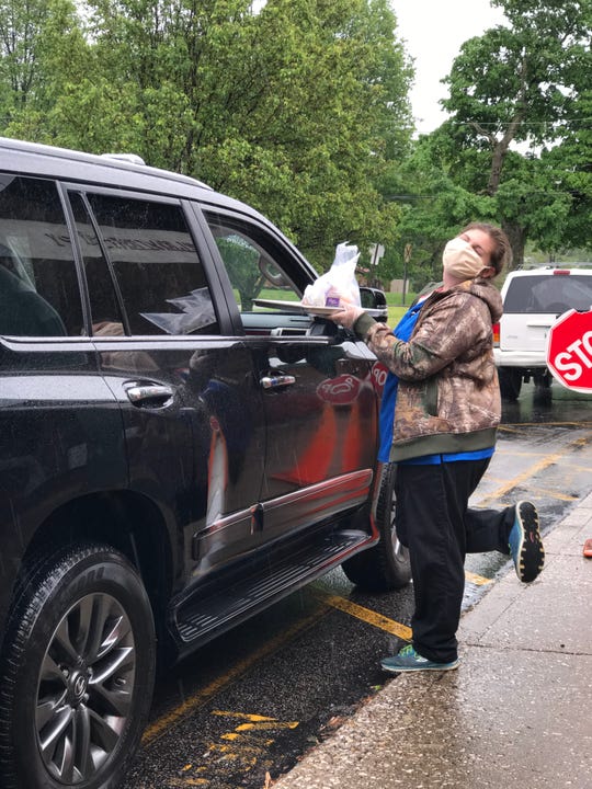 A worker with the Warrick County School Corp. in southern Indiana carries a tray of several pre-packaged breakfasts and lunches to a waiting car on Friday. May 8, 2020. Food service coordinators there estimate their meal program has lost $500,000 since March due to decreased revenue and increased expenses related to COVID-19.