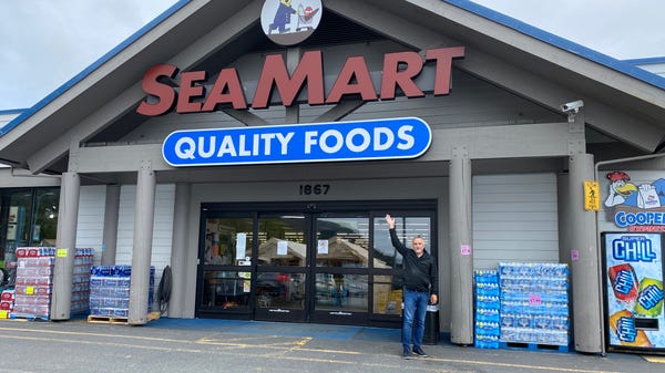 Grocer Max Rule poses in front of his store, Sea M