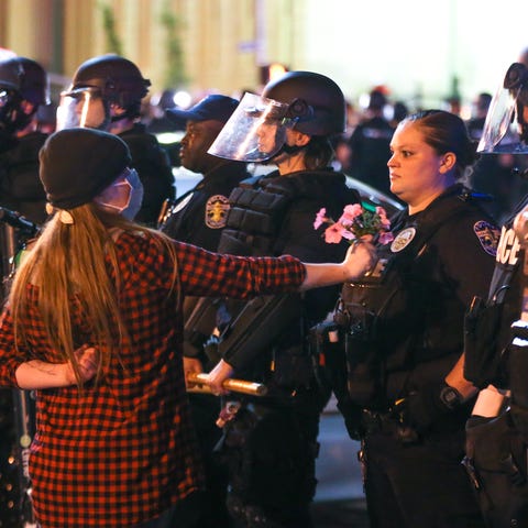 A protester offers a police officer flowers during