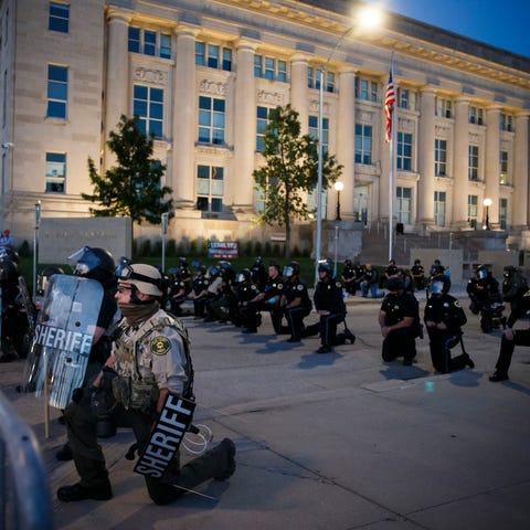 Officers and protestors take a knee in front of th