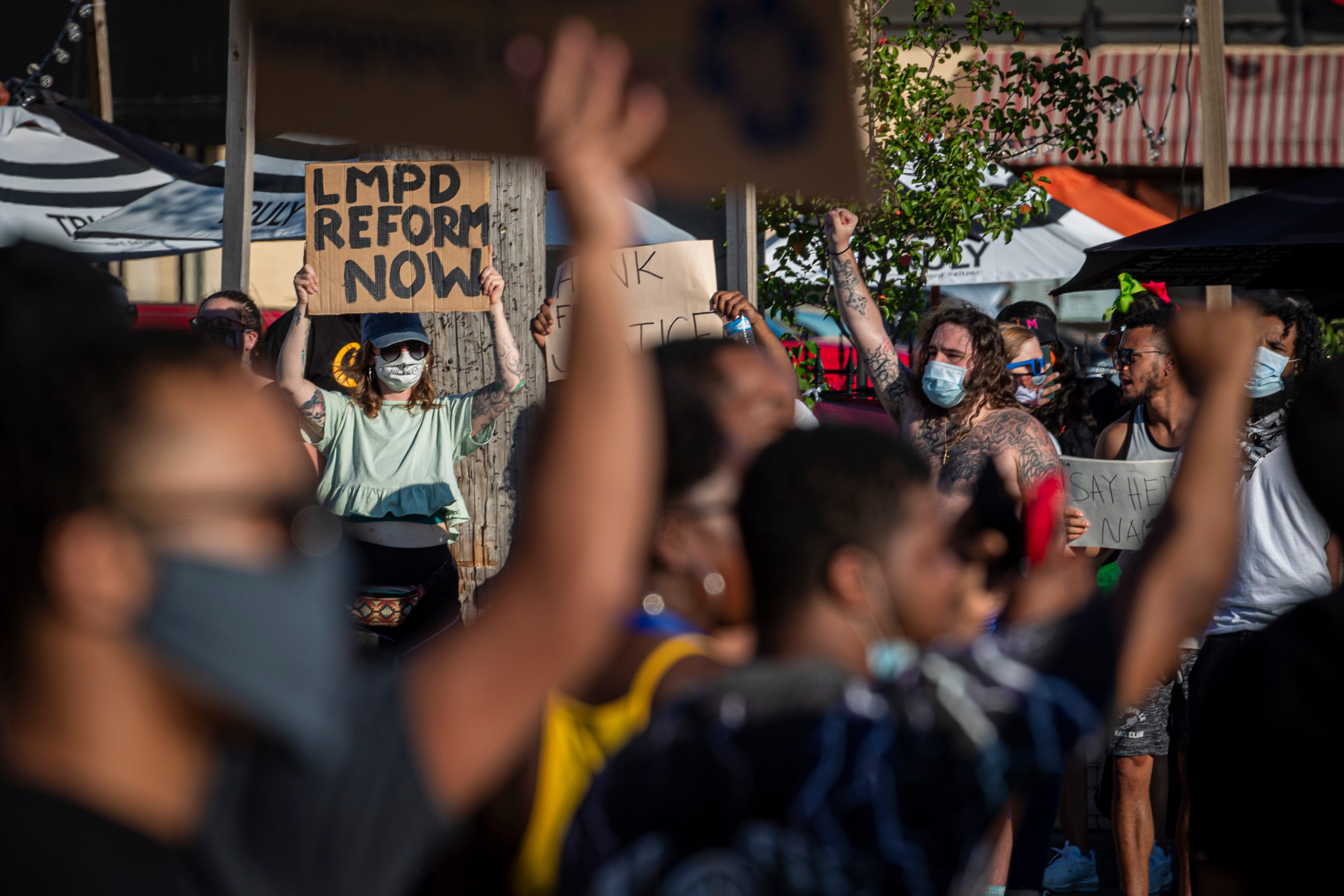 Protesters hold signs in downtown St. Matthews on Wednesday. June 3, 2020