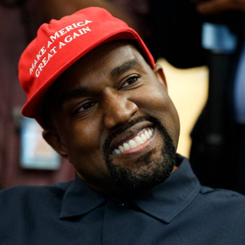 Rapper Kanye West smiles as he listens to a questi