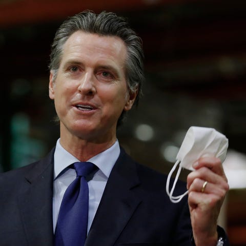 Gov. Gavin Newsom displays a face mask as he urges