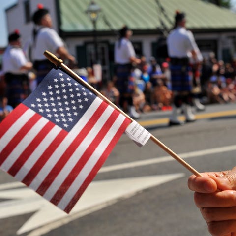 Parade spectators wave American flags during a Vir