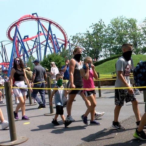 People wear masks as they arrive for Six Flags Gre