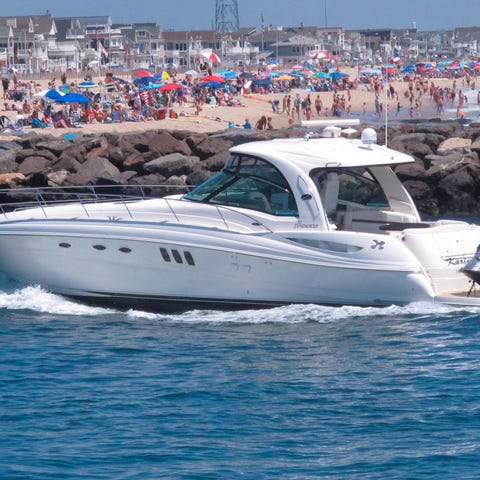 A yacht cruises through the Manasquan Inlet as peo