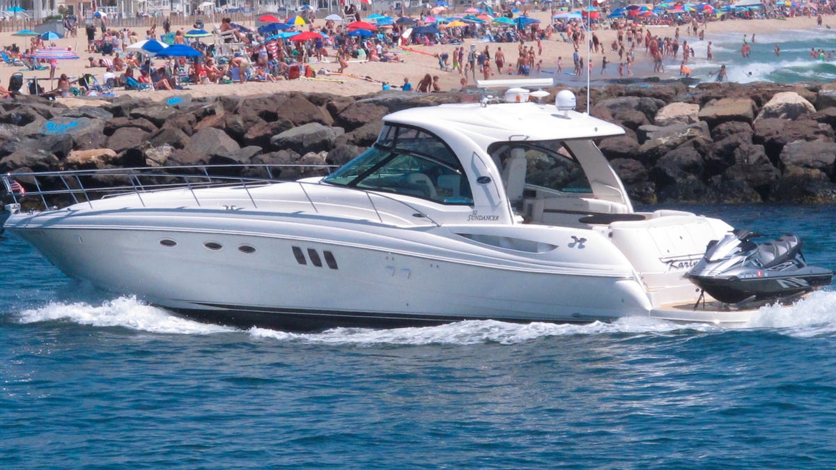 A yacht cruises through the Manasquan Inlet as people crowd the beach on the Jersey Shore in Manasquan, N.J., on June 28.