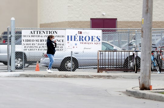 An American Foods Group employee walks past a sign that says “Heroes trabajan aquí,” meaning “Heroes work here,” on April 28 in Green Bay.