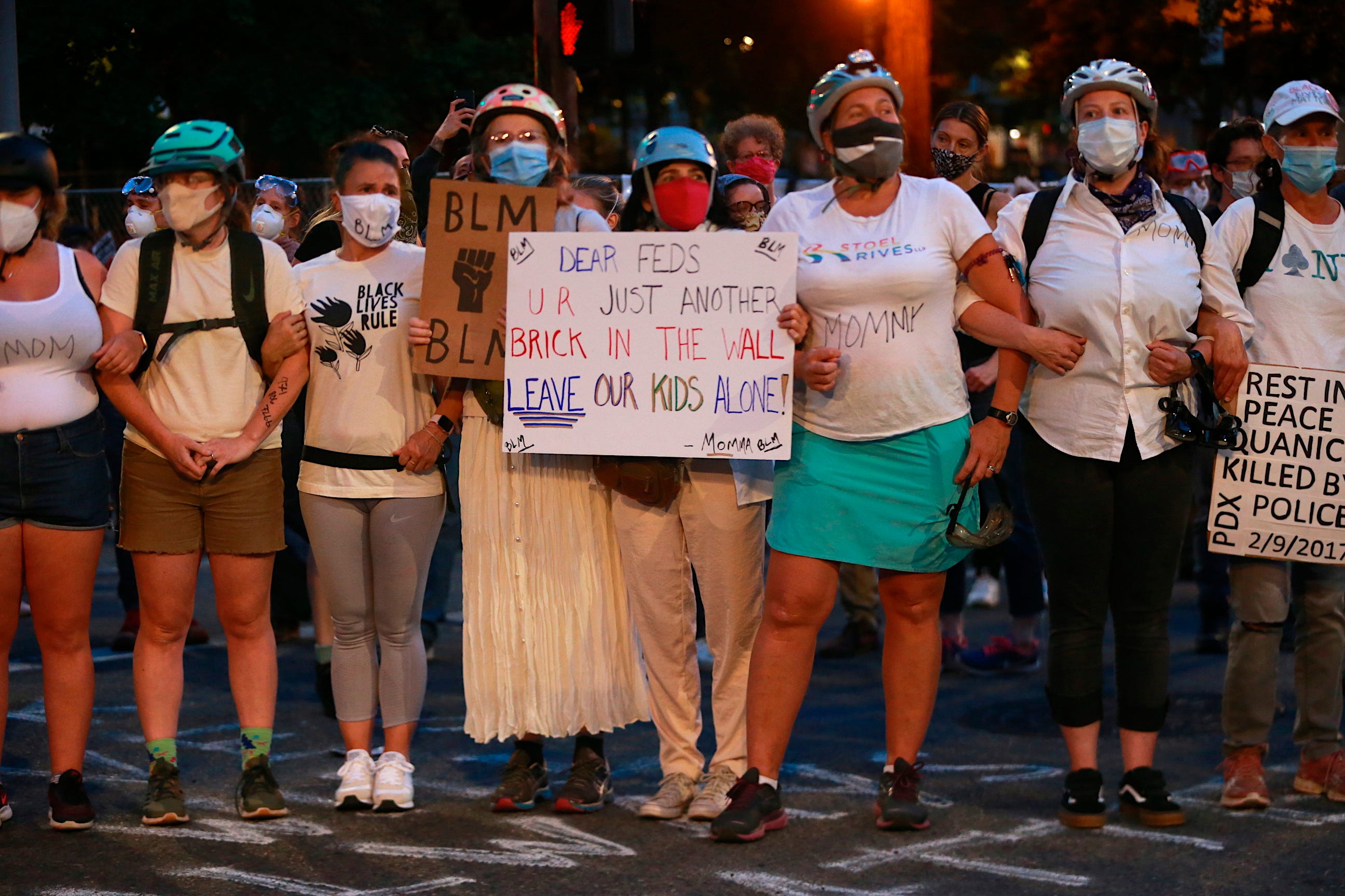 Mothers stand arm-in-arm outside the Justice Center in downtown Portland, Oregon, on July 18 during another night of protests. Activists and lawmakers expressed outrage over accusations that federal agents circulating in unmarked cars grabbed protesters off the streets.