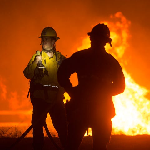 Firefighters keep watch a brush fire at the Apple 