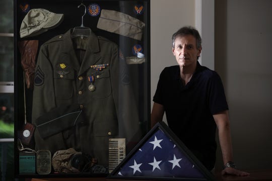 Mitchell Bierman poses with WWII mementos his father, Mel Bierman kept from WWII and a flag. Bierman was one of 27 people the United States sent into the air during the bombing of Hiroshima, which took place 75 years ago this week. Bierman, who was born in 1922, grew up in Passaic and died in 2013. Monday August 3, 2020