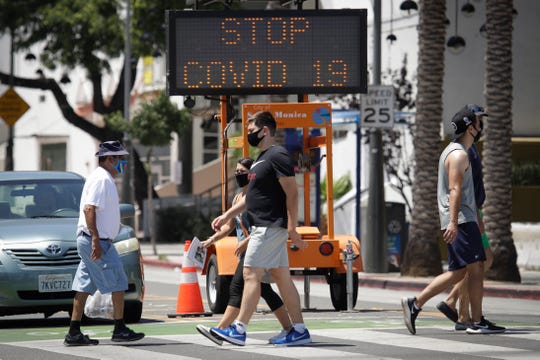 Pedestrians wear masks as they cross a street amid the coronavirus pandemic in Santa Monica, California. A heat wave has brought crowds to California's beaches as the state grappled with a spike in coronavirus infections and hospitalizations.