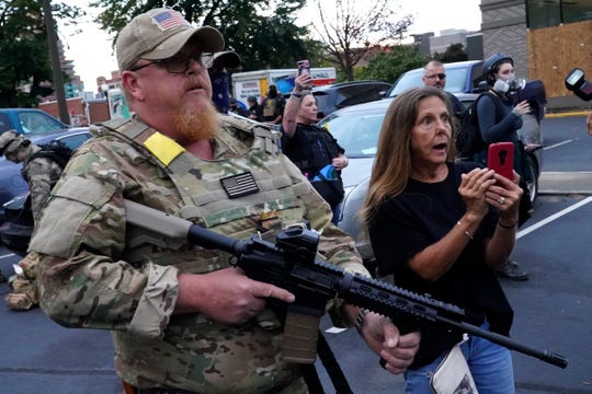 An armed counter-protester talks with Black Lives Matter demonstrators on Thursday in Louisville, Ky.