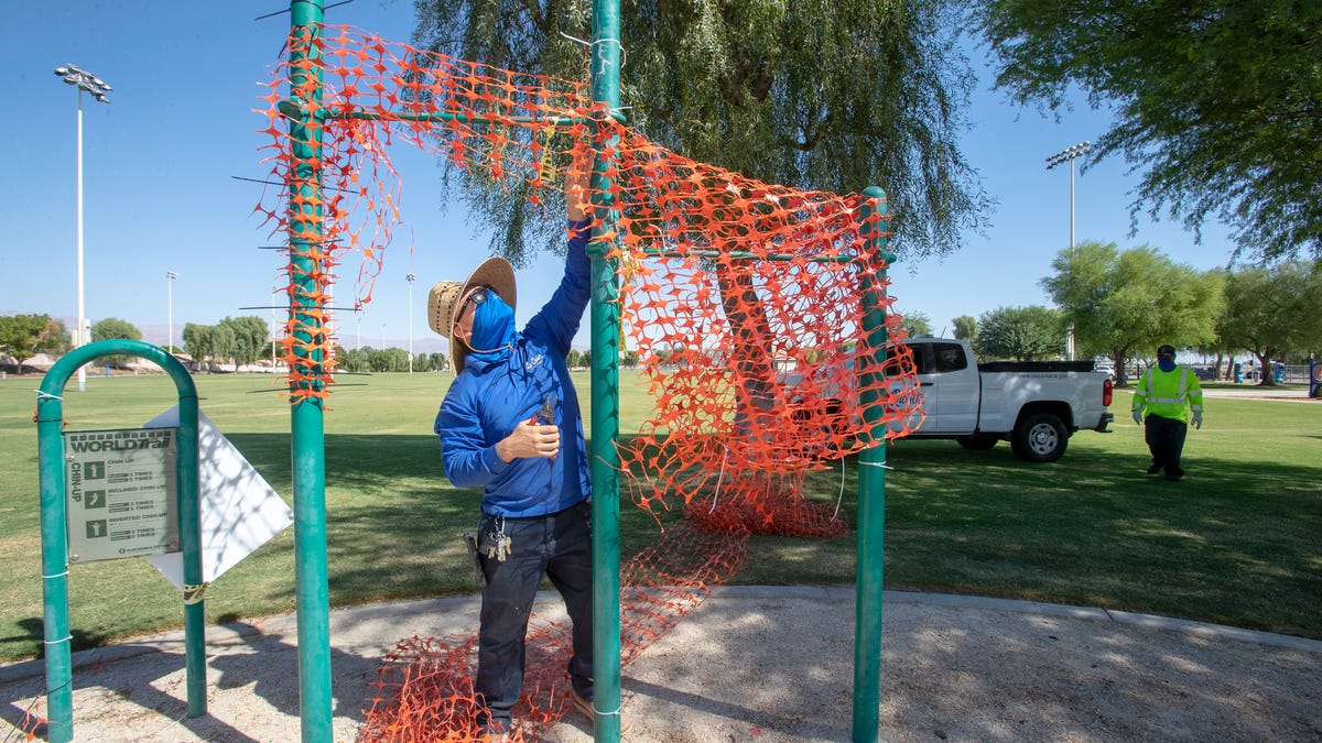 City of La Quinta employee, Armando Cabrera, removes a netting barrier from exercise equipment at La Quinta Park in La Quinta, Calif., on September 29, 2020. Gov. Newsom announced that all playgrounds can reopen across California, masks and social distancing are required.