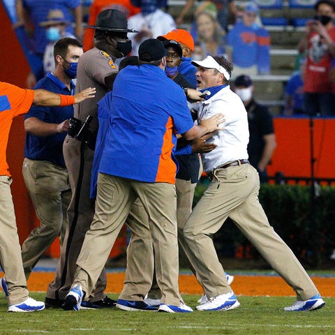 Florida coach Dan Mullen, right, is held back by c