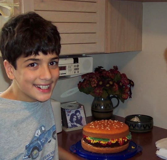 Jonny Manganello as a child in Grosse Pointe with his first cake, which he designed to resemble a cheeseburger. 