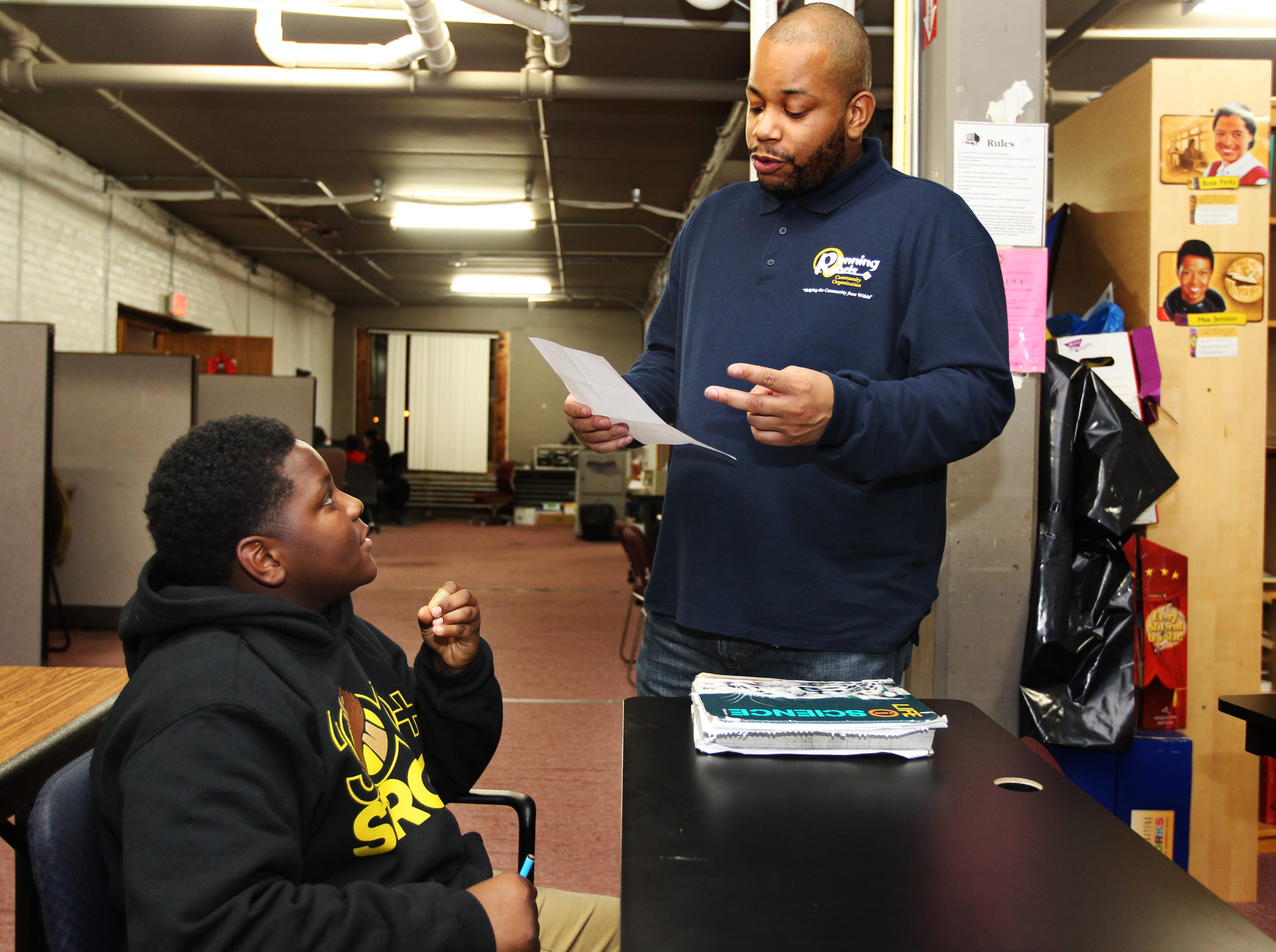 Keelyn Tyler, right, a mentor at Running Rebels, helps Davieon Lewis, 12, with his science homework on Dec. 20, 2017.