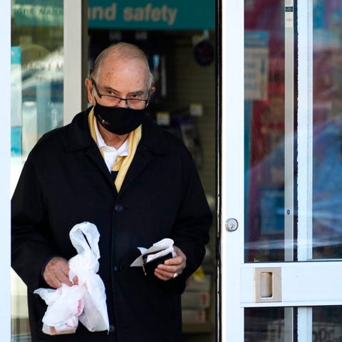 A customer wears a mask as he walks out of a Walgr