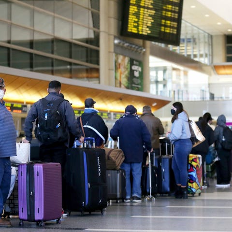 Travelers wait in line to check in for a flight at